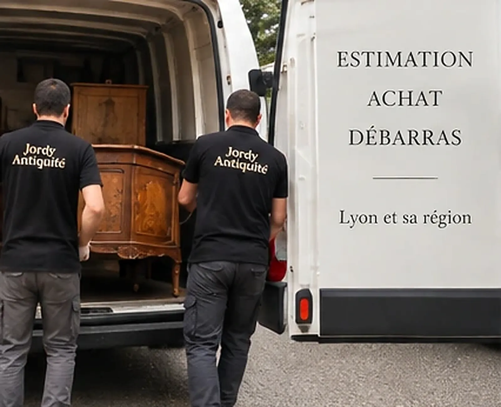 Deux membres de l'équipe en polo noir chargent une commode ancienne en bois dans une camionnette blanche