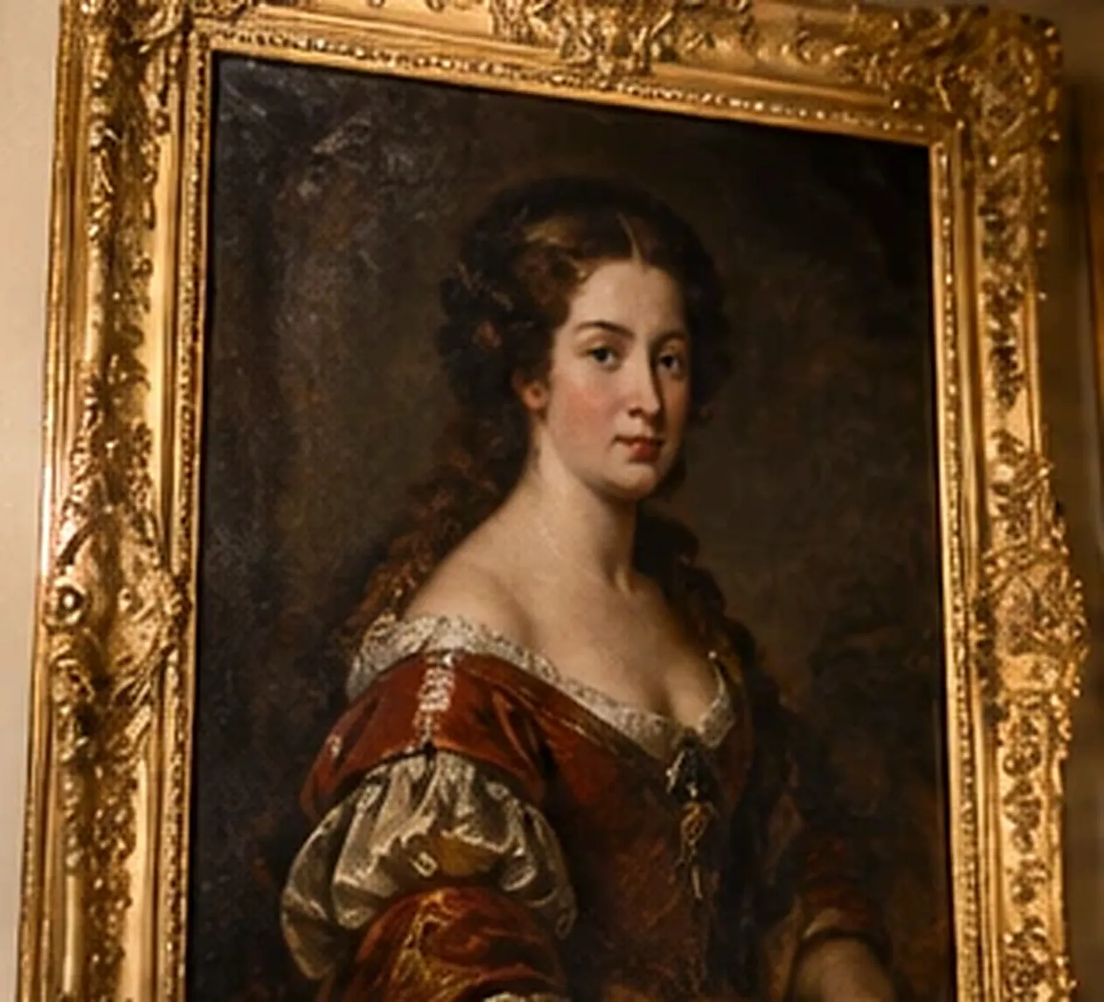 Tableau ancien représentant le portrait d'une jeune femme en robe de velours rouge, dans un cadre doré richement sculpté